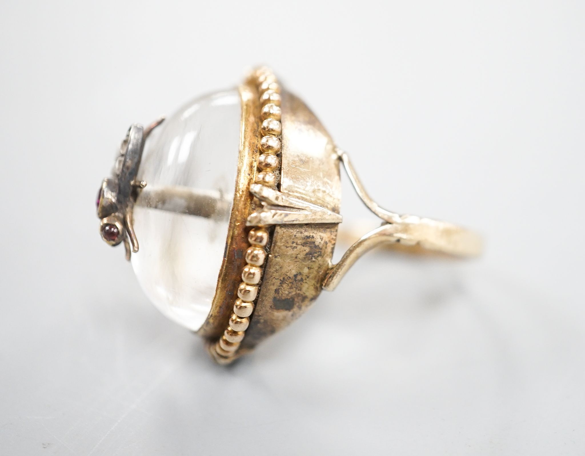 A Victorian, yellow metal and cabochon rock crystal? set dress ring, with central gem set bug motif, size R/S, gross weight 12.4 grams.